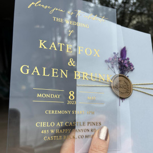 Clear Acrylic wedding invitation, Gold foil print, Parchment wrap, Gold wax seal and purple flowers.